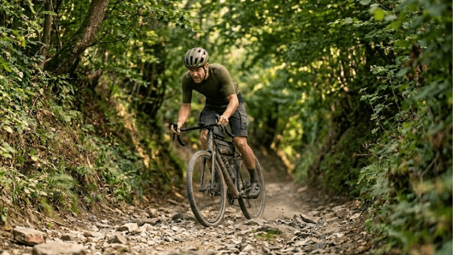 Een gravelbiker fietst door een steile, onverharde holle weg met een grove, rotsachtige ondergrond, onderdeel van de mooiste gravelroutes in Nederland in Zuid-Limburg.