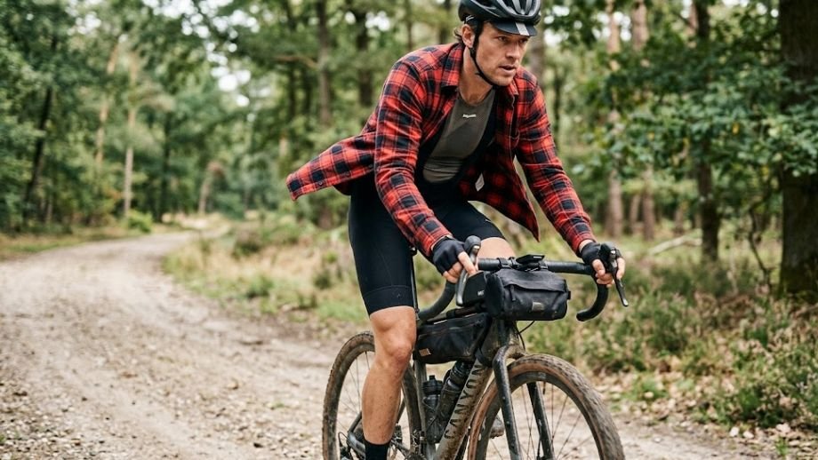 Het Mullet Protocol in gravelbike kleding: een casual flanellen shirt gedragen over een strakke bibshort.